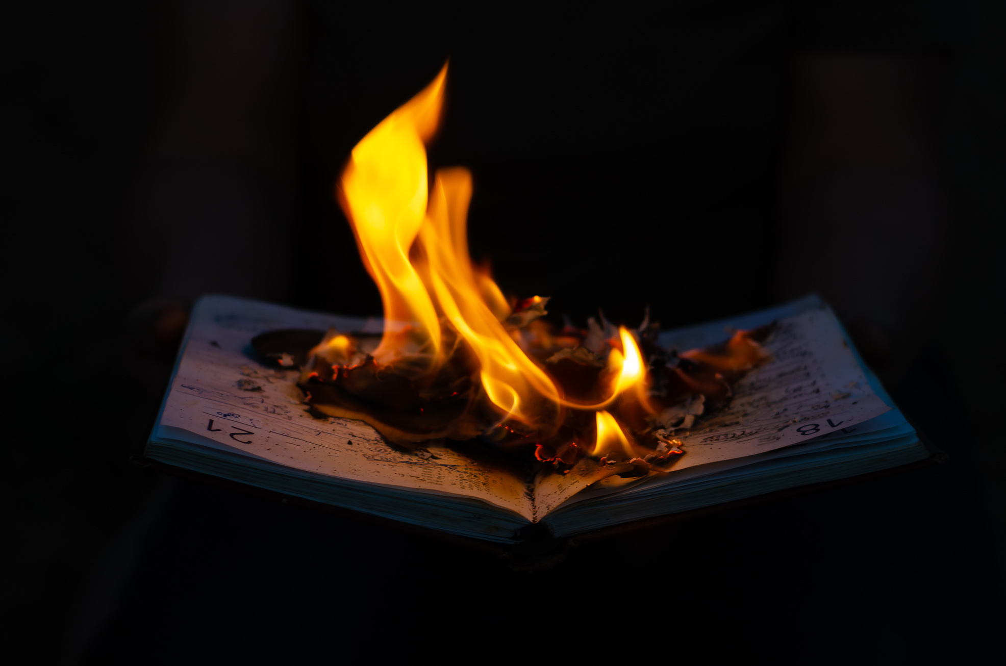 Open Burning Diary on Black Background. Notebook with Flame Cove